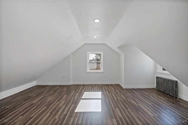 additional living space with radiator, dark wood-type flooring, and lofted ceiling