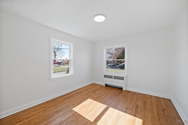 unfurnished room featuring radiator and light wood-type flooring