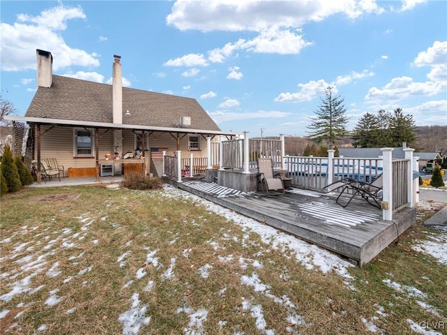 rear view of property featuring a lawn and a wooden deck