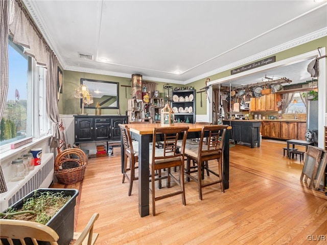 dining room with light hardwood / wood-style flooring, plenty of natural light, and ornamental molding