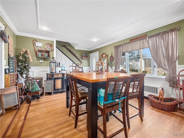 dining room featuring ornamental molding, radiator heating unit, and light hardwood / wood-style flooring