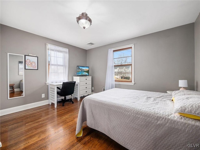 bedroom with dark hardwood / wood-style flooring and multiple windows