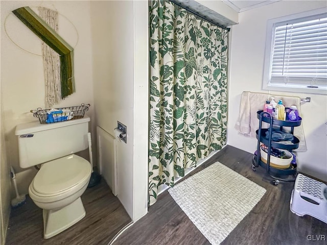 bathroom with hardwood / wood-style flooring, toilet, and crown molding