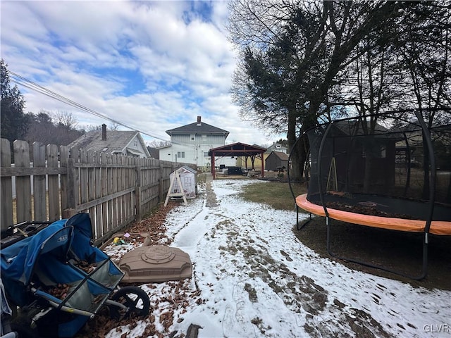 snowy yard with a gazebo, a trampoline, and a storage shed