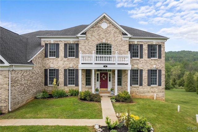 colonial inspired home with a balcony and a front lawn