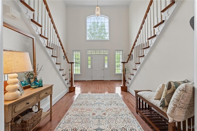 entryway with a towering ceiling, ornamental molding, and hardwood / wood-style flooring