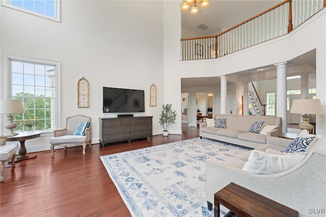 living room featuring a high ceiling, dark hardwood / wood-style flooring, and ornate columns