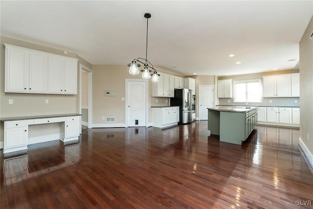 kitchen featuring dark hardwood / wood-style flooring, pendant lighting, white cabinets, stainless steel fridge with ice dispenser, and a kitchen island