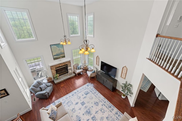 living room featuring a fireplace, a high ceiling, dark hardwood / wood-style floors, and a notable chandelier