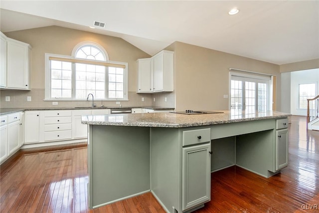 kitchen with green cabinets, white cabinetry, a center island, and vaulted ceiling