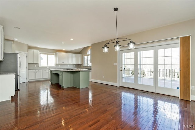 kitchen featuring stainless steel refrigerator, white cabinetry, a wealth of natural light, pendant lighting, and a kitchen island