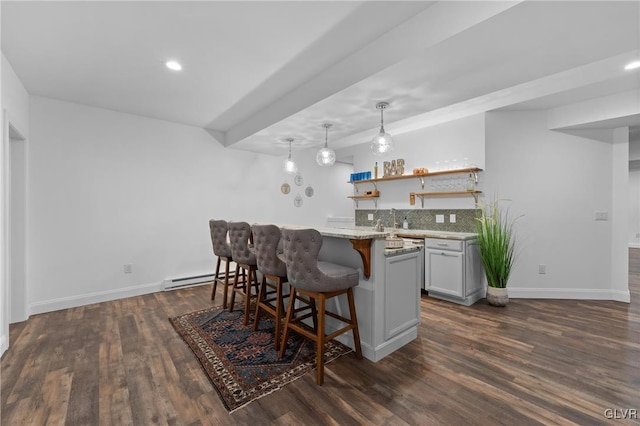 kitchen featuring pendant lighting, dark wood-type flooring, a kitchen breakfast bar, light stone countertops, and tasteful backsplash