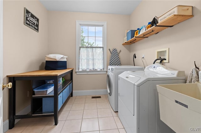 laundry area with separate washer and dryer, sink, and light tile patterned flooring