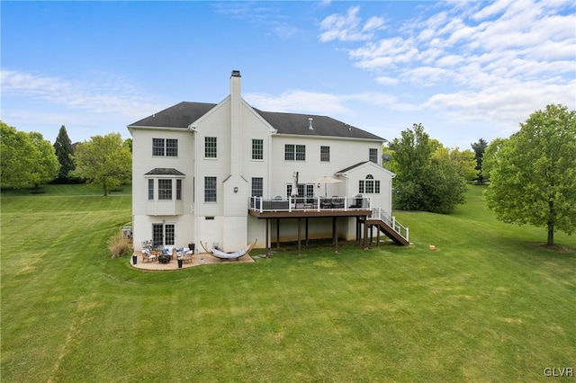 rear view of property featuring a lawn and a deck