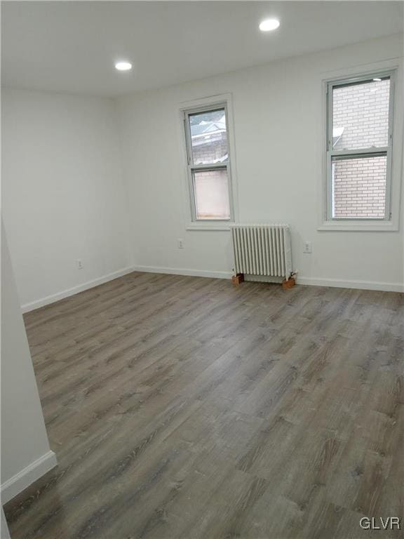 empty room featuring radiator heating unit and dark hardwood / wood-style floors