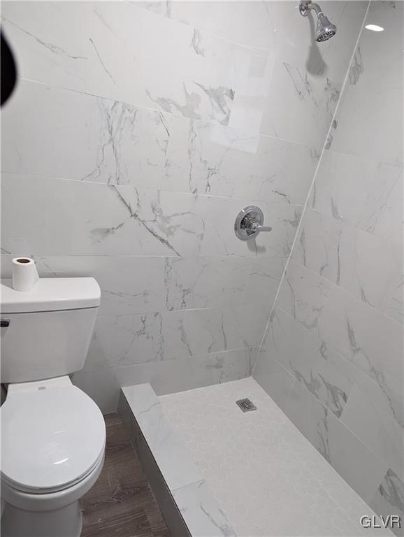 bathroom with toilet and a tile shower