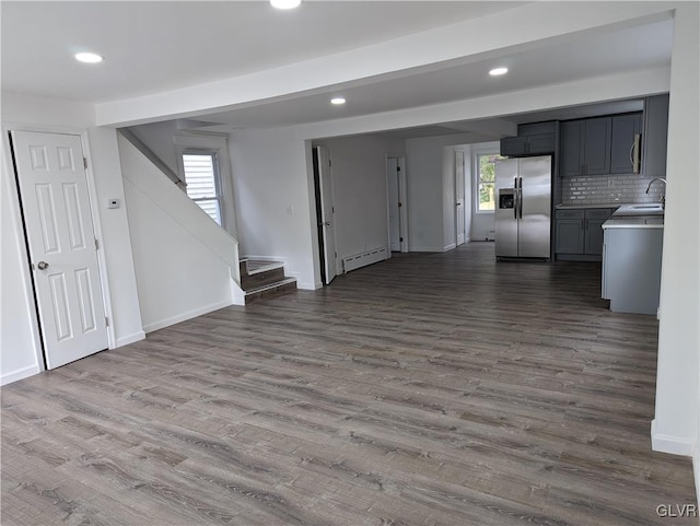 unfurnished living room featuring dark hardwood / wood-style flooring, a baseboard radiator, a wealth of natural light, and sink