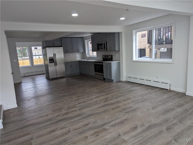 kitchen with tasteful backsplash, gray cabinetry, a baseboard radiator, and appliances with stainless steel finishes