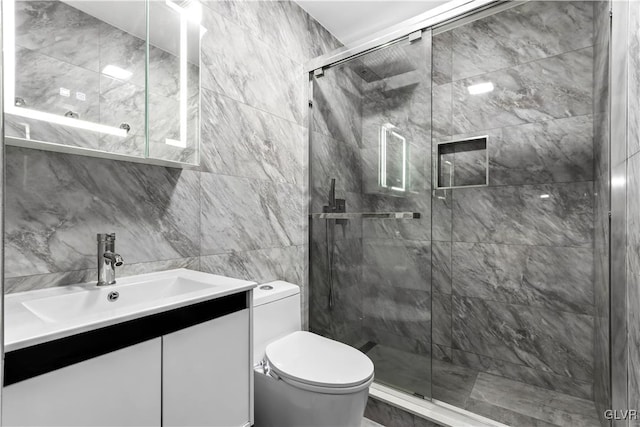 bathroom with vanity, toilet, a shower with door, and tile walls