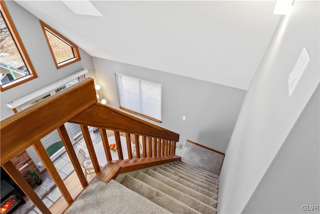 stairs featuring carpet floors and lofted ceiling with skylight