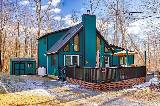 rear view of house with a wooden deck and a shed