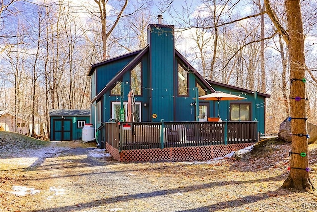 rear view of property featuring a shed and a deck