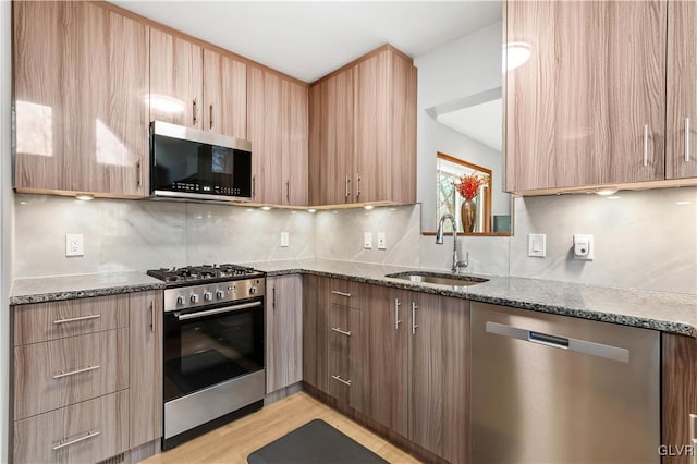 kitchen featuring dark stone countertops, decorative backsplash, sink, and appliances with stainless steel finishes