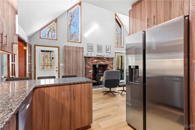 kitchen featuring stainless steel appliances, high vaulted ceiling, dark stone countertops, kitchen peninsula, and light hardwood / wood-style floors