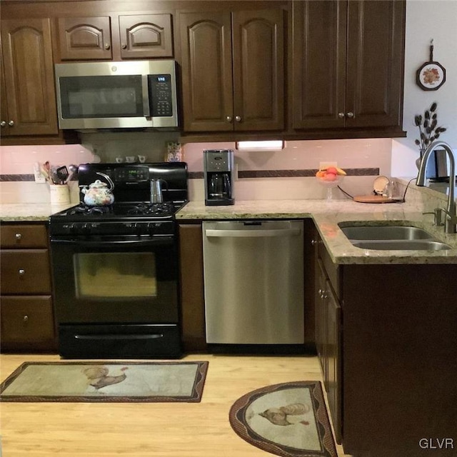 kitchen featuring dark brown cabinetry, sink, stainless steel appliances, and light wood-type flooring