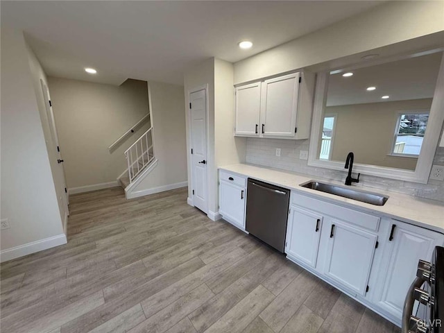 kitchen with tasteful backsplash, dishwasher, sink, white cabinetry, and light wood-type flooring