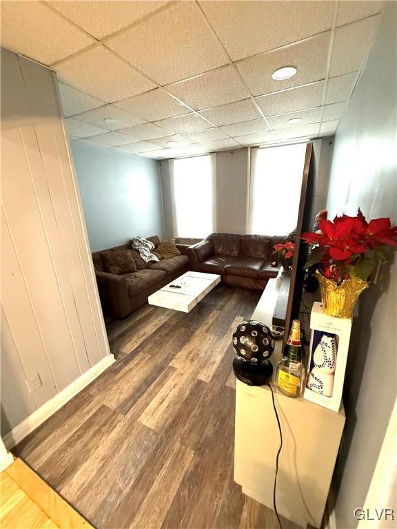 living room with a paneled ceiling and dark hardwood / wood-style flooring