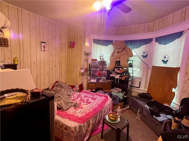 bedroom with ceiling fan, carpet floors, and wood walls