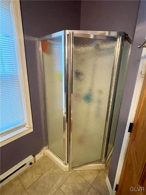 bathroom with tile patterned flooring, a shower with door, and a baseboard heating unit