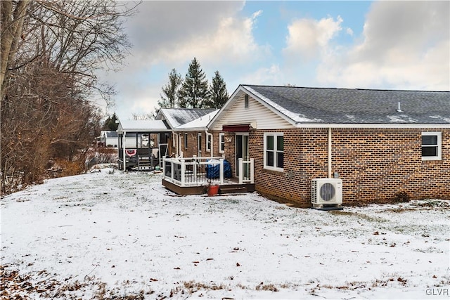 snow covered house with a wooden deck and ac unit