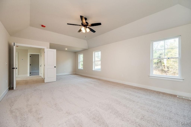 carpeted spare room with lofted ceiling, a raised ceiling, and ceiling fan