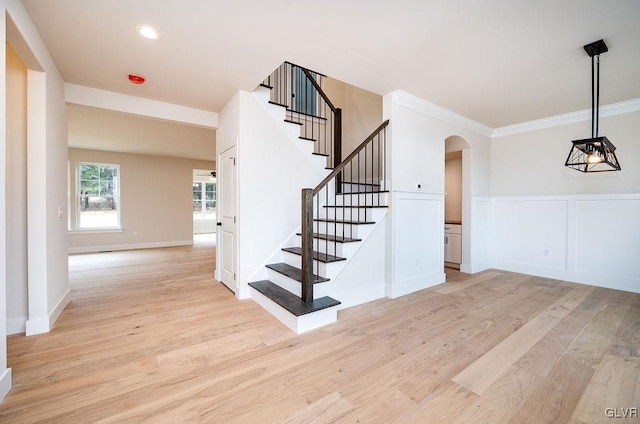 stairs with ornamental molding and wood-type flooring