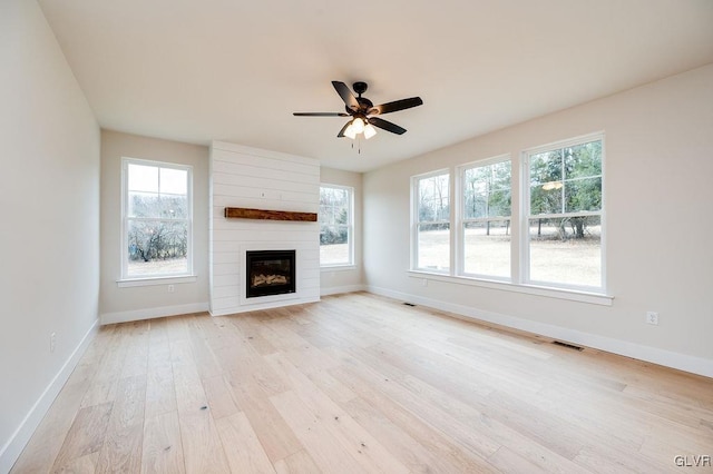 unfurnished living room featuring a fireplace, ceiling fan, and light hardwood / wood-style flooring