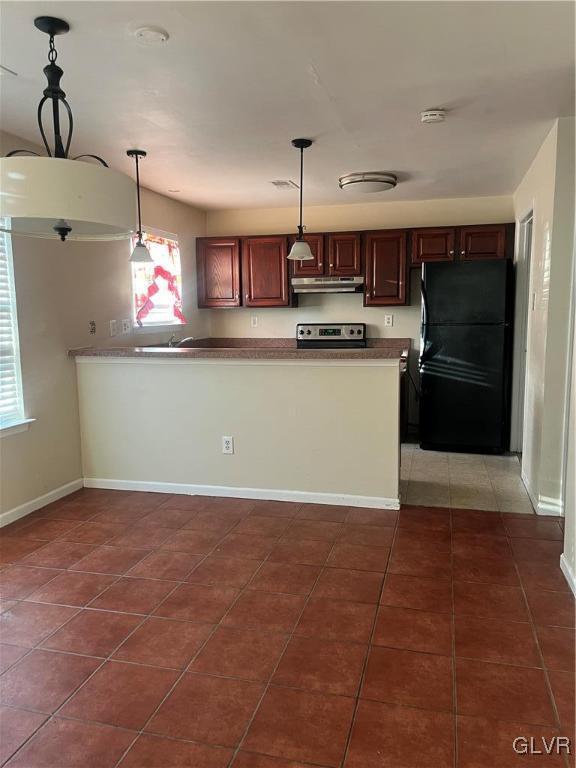 kitchen featuring pendant lighting, black refrigerator, dark tile patterned floors, and stainless steel electric stove