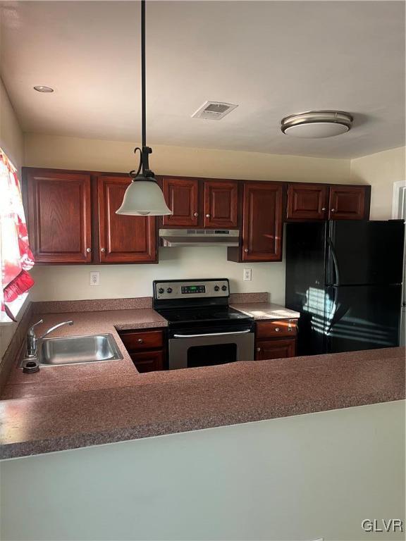 kitchen with electric range, black refrigerator, sink, and pendant lighting