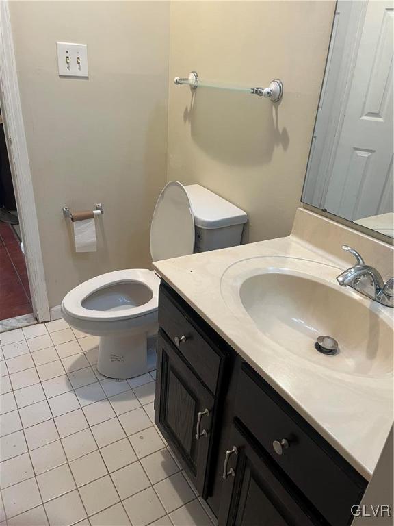 bathroom with toilet, vanity, and tile patterned floors