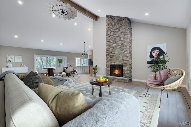 living room featuring vaulted ceiling with beams, light hardwood / wood-style floors, and a stone fireplace