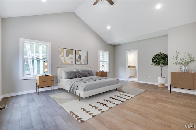 bedroom featuring ceiling fan, light hardwood / wood-style floors, ensuite bathroom, and multiple windows