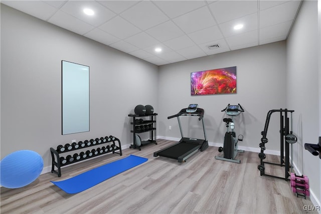 workout room with light hardwood / wood-style flooring and a drop ceiling