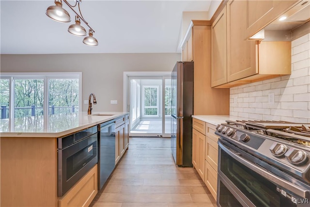 kitchen featuring light brown cabinets, sink, appliances with stainless steel finishes, tasteful backsplash, and decorative light fixtures