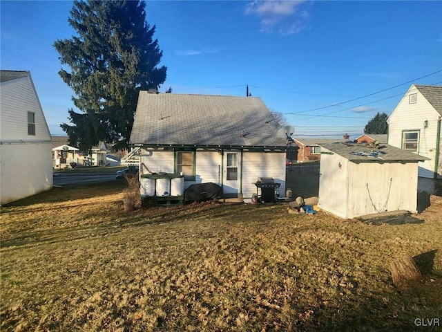 back of property featuring a storage unit and a lawn