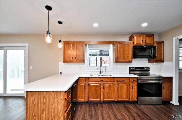 kitchen featuring dark hardwood / wood-style floors, kitchen peninsula, electric range, sink, and hanging light fixtures