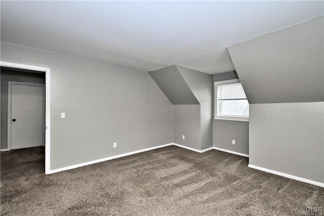 additional living space featuring vaulted ceiling and dark colored carpet