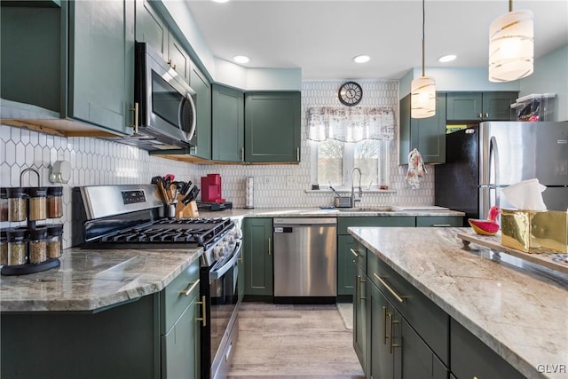 kitchen featuring light stone countertops, stainless steel appliances, hanging light fixtures, and green cabinets