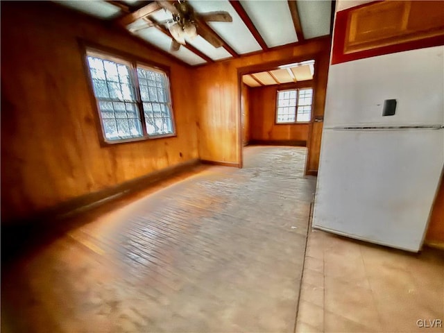 empty room featuring ceiling fan and wooden walls