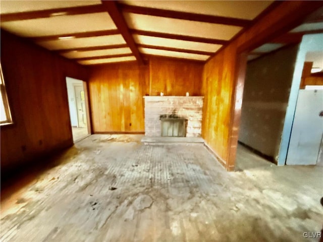 unfurnished living room featuring wood walls, vaulted ceiling, and a stone fireplace